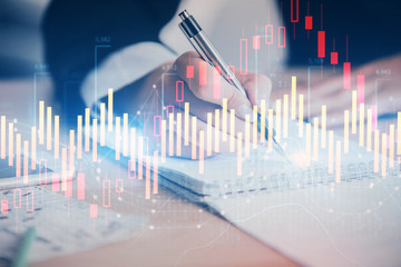 A woman hands writing information about stock market in notepad. Forex chart holograms in front. Concept of research. Multi exposure