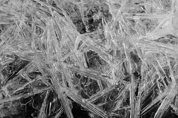 Transparent white frozen ice crystals as crack texture on black background, winter seasonal backdrop