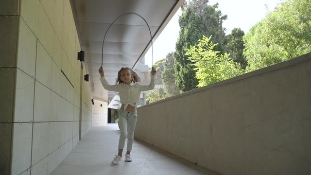 Junior girl jumping up, holding rope in hands