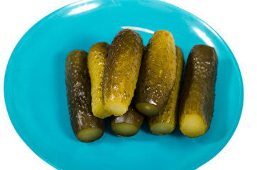 Salted cucumbers lie on a blue plate on a white background