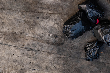 Many black garbage bags that are tied up On the sidewalk, roughly the footpath, viewed from the top view