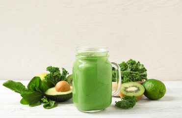 Tasty fresh kale smoothie on white wooden table