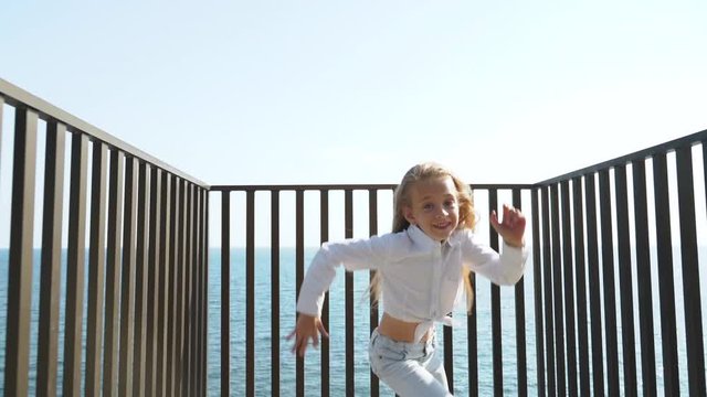Youngster girl running near metal fence, making nice smile