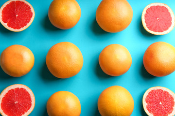Cut and whole ripe grapefruits on blue background, flat lay