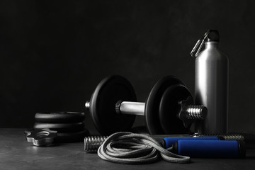 Gym equipment and accessories on stone floor against dark background