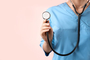 Doctor with stethoscope on pink background, closeup. Medical service