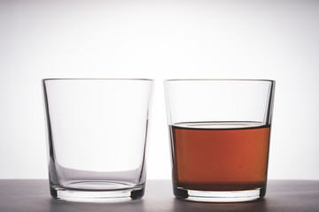 two glass glasses on the table, one glass empty, the second glass with alcohol, tinted image, selective focusing, vignetting