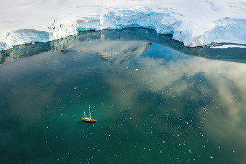 Fototapeta premium aerial view to yacht in lagoon under huge glacier