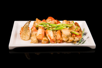 crab legs in a batter with green onions on a black background