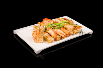 crab legs in a batter with green onions on a black background