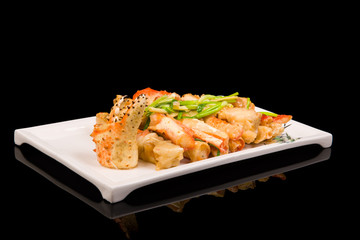 crab legs in a batter with green onions on a black background