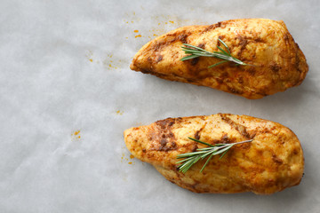 Grilled chicken breast with rosemary on a parchment paper with copy space on the left side. Selective focus. Top view photo. 