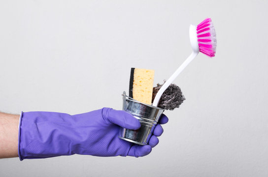 Man wearing protective glves for cleaning and holding little bucket full of supplies for washing, cleaning house