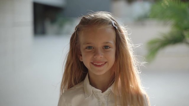 Teen girl smiling wide, standing against architecture background
