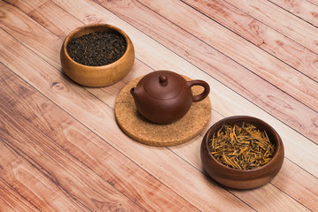 Chinese tea in Yixing clay teapot and wooden bowls stand on aged wooden table.