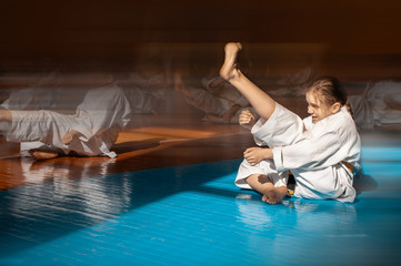 Fototapeta na wymiar A teenage girl with a yellow belt in a karate class trains a direct kick. Beautiful morning light. Oriental martial arts. Children's training. No faces. With place for text.