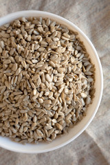 Overhead view, Raw Sunflower Seed Kernels in a white bowl. Flat lay, top view, from above.