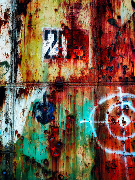 Contrast metal door of an abandoned hangar with red, yellow and green paint. Old grunge metal door.