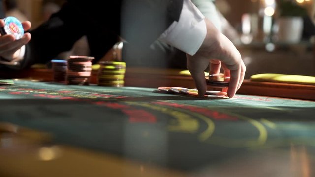 Slow motion close up shot of croupier laying out poker chips on casino table