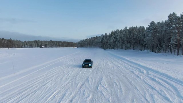Aerial shot of car driving full speed on a snow track in winter landscape