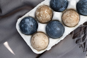 natural-dye Easter eggs lying in tray . Background with easter eggs. Naturally dyed eggs prepared for Easter on gray texture tablecloth background. Happy Easter card. 