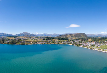 Fototapeta na wymiar Beautiful panoramic high angle aerial drone view of the town of Wanaka, a popular ski and summer resort town located at Lake Wanaka in the Otago region of the South Island of New Zealand.