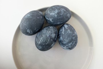 Naturally dyed blue eggs prepared for Easter on white background. Happy Easter card. Easter background with Easter eggs in a ceramic gray bowl. Background with easter eggs. Top view 