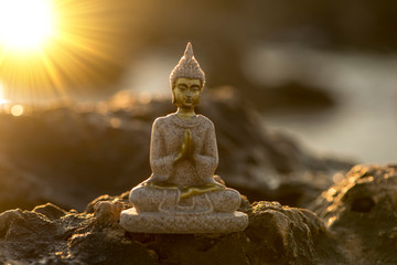 A buddha figure on a rock by the sea