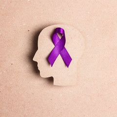 Purple awareness ribbon and head silhouette on a brown background.