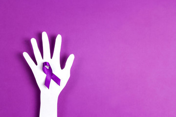 Purple awareness ribbon and paper hand silhouette on a purple background.