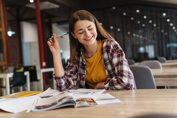 Image of smiling caucasian girl doing homework with exercise books