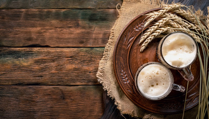 Dark beer in the mug on the wooden table background with copy space.