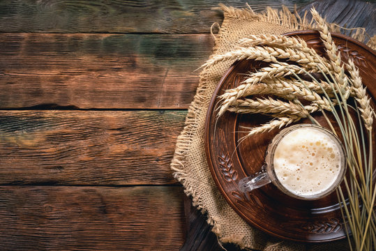 Dark beer in the mug on the wooden table background with copy space.