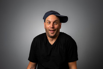 man in black vneck teeshirt and backwards hat