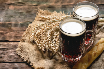 Dark beer in the mug on the wooden table background.