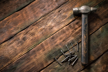 Hammer and nails on wooden brown workbench background with copy space.