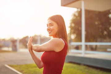 Young woman exercising / stretching in urban park.