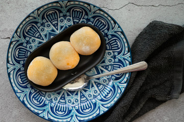 Yellow-colored Japanese Mochi in rice dough and on a pattern blue plate background. Traditional Japanese dessert.