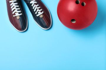 Bowling ball and shoes on light blue background, flat lay. Space for text