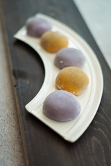 Multi-colored Japanese Mochi in rice dough and on a wooden background. Traditional Japanese dessert.