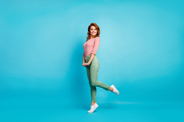 Obraz premium Full length profile photo of pretty lady enjoy warm spring day traveling abroad wear casual red white shirt green pants footwear isolated blue color background