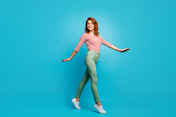 Full length profile photo of funny pretty lady enjoy warm spring day spend time walk street wear casual red white shirt green pants shoes isolated blue color background