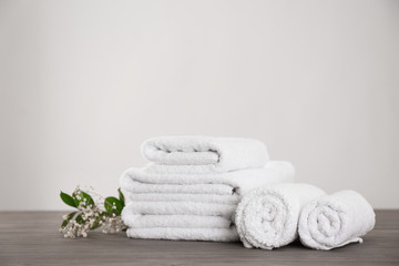 Fototapeta na wymiar Fresh white towels and green plant on grey wooden table