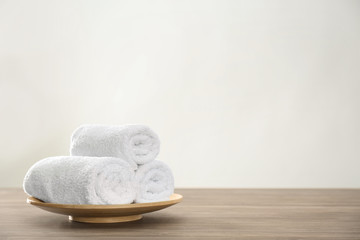 Fresh rolled towels on wooden table. Space for text