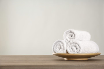 Fresh rolled towels on wooden table. Space for text