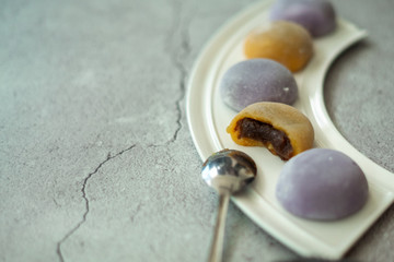 Multi-colored Japanese Mochi in rice dough and on a beautiful plate and concrete background. Traditional Japanese dessert.