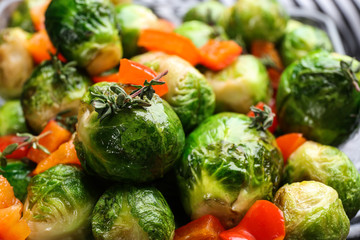 Delicious roasted Brussels sprouts with bell pepper as background, closeup
