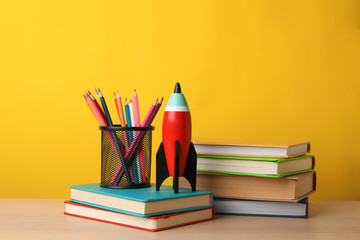 Fototapeta premium Bright toy rocket and school supplies on wooden table