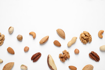 Different delicious nuts on white background, flat lay. Space for text