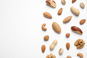 Different delicious nuts on white background, flat lay. Space for text